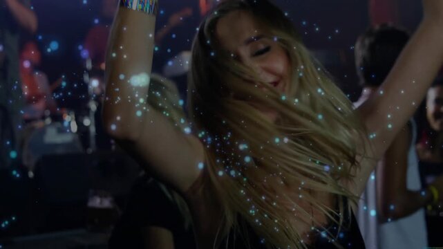 Woman dancing at music concert under colored lights, blue particle effects floating around stage