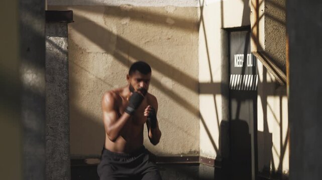 Young man with toned body practicing punches while shadow boxing on a rooftop