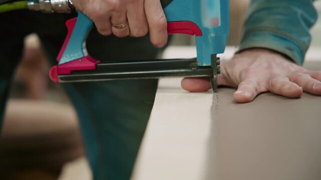Craftsman using pneumatic staple gun on furniture