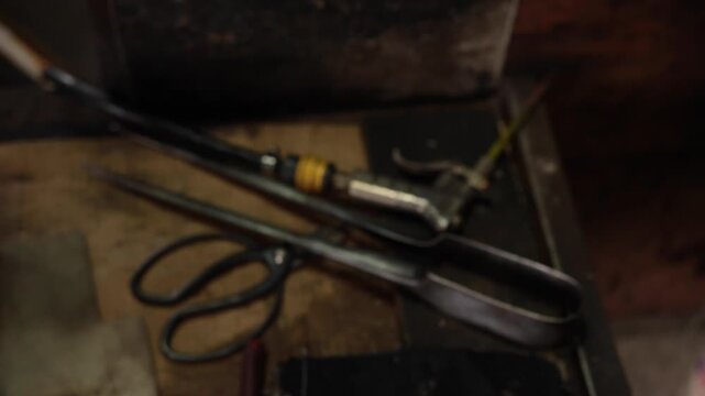 琉球ガラス工房内の作業台に置かれた職人の道具（エア、洋バシ、ハサミ）