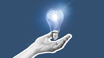 Light bulb held in hand with a brain inside shining light in a creative concept