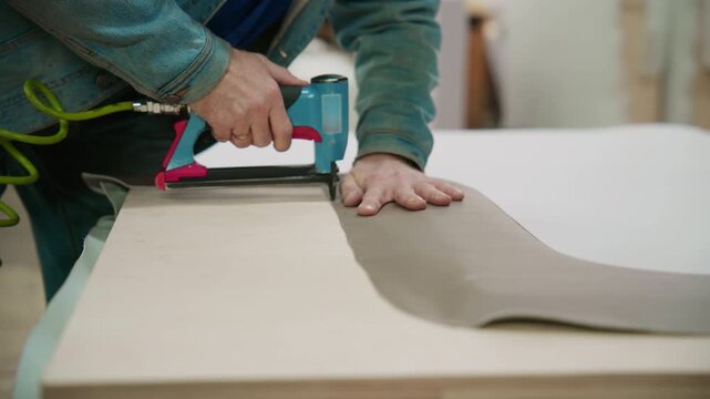 Upholsterer using pneumatic staple gun on furniture