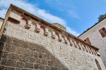 Low angle architectural detail of the stone facade of the Church of Saint Luke with arched cornices and blue sky in the historic district © Javier
