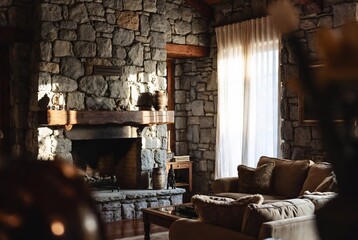 Fototapeta premium A cozy stone-walled living room with a fireplace and comfortable furniture.