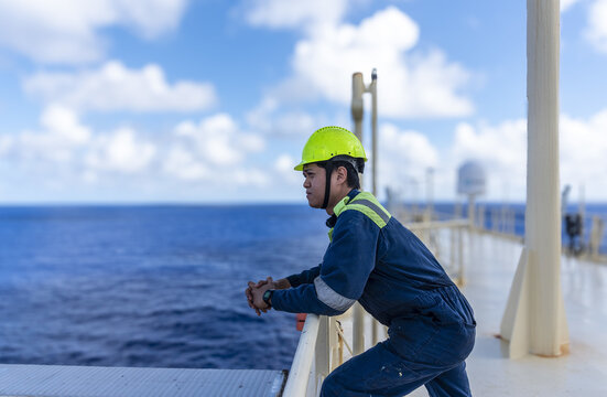 Seafarer in protective gear climbing vertical ladder on ship&rsquo;s navigation mast during routine maintenance.