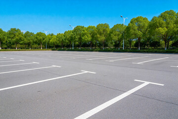 Obraz premium Empty Parking Lot with Green Trees and Clear Sky