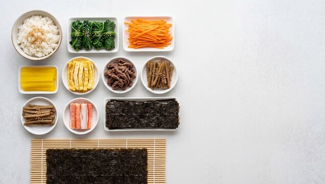 김밥을 만들기 위한 신선한 재료들이 하얀 배경 위에 정갈하게 배열된 모습.