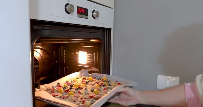 Placing Baking Tray with Food into Preheated Oven. Not recognizable people.