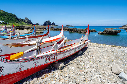 Lanyu, Taiwan - June 24, 2025: Traditional Tao plank boats on the shore with volcanic bay view.