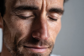 Obraz premium A close-up portrait of a man with a relaxed expression and closed eyes, conveying feelings of tranquility and introspection while highlighting facial features and textures.