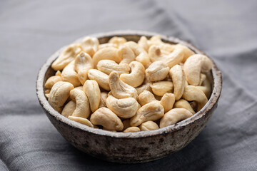 Dry cashew nuts in bowl, grey background, healthy vegan snack