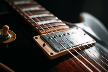 Fototapeta premium A guitar rests on a wooden table with soft light highlighting its body and strings. Knobs and switches catch the light. The room has a warm atmosphere as music fills the air