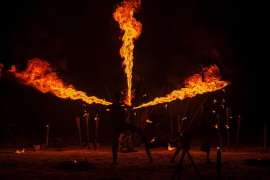 Silhouette Thai performers show fire breathing and spinning on beach