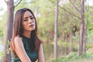 Naklejka premium Portrait Asian Woman relaxing in green park. Happy Relax asian woman smiling face at outdoors garden. Young women enjoy nature freedom lifestyle. Greenery wellbeing outside beauty in nature.