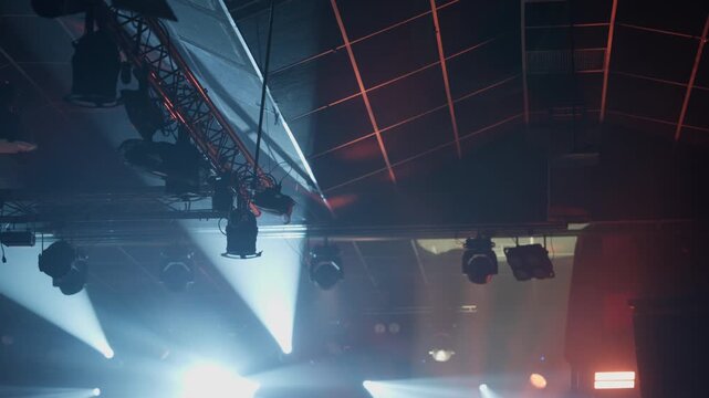 Mesmerizing display of moving stage lights and spotlights cutting through atmospheric smoke in a dark concert hall or event venue