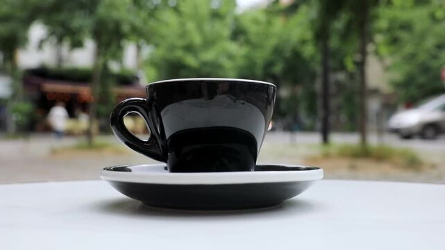 Cup of fresh hot coffee on the table of an outdoor cafe in Paris, France.