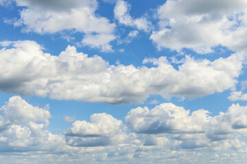 Fototapeta premium Blue cloudy sky. Beautiful blue sky with many white fluffy cumulus clouds in sunlight background texture