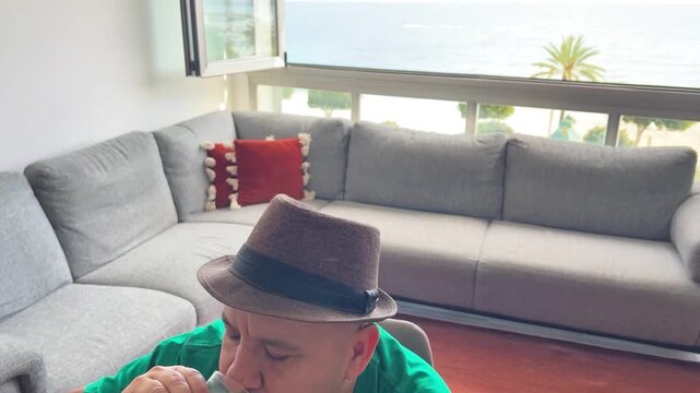 Hombre tomando zumo de naranja con vistas al mar