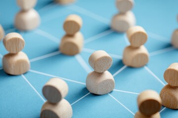 Obraz premium Networking of Wood Figures: A macro shot showcases a network of interconnected wooden figures, symbolizing the essence of human connection. The figures are placed on a blue background.