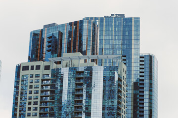 Fototapeta premium Skyscrapers stand tall with glass facades reflecting the sky in an urban setting during the daytime