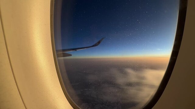 Beijing,China-03 12 26:View from airplane window showing a wing of Air China aircraft flying sunset on a transatlantic journey, warm golden light in sky clouds below. Destination travel concept