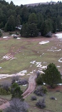 Aerial winter mountain meadow with snow mud trails and ATV adventure