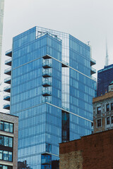 Obraz premium Modern building in urban area with glass exterior and balconies located in a busy city setting during daytime hours