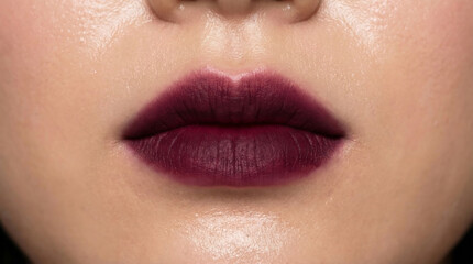 Fototapeta premium Close-up of lips with matte dark plum lipstick in beauty fashion photo.