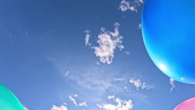 Colorful balloons drift in from the edges against a bright blue sky, changing positions across the frames and forming a festive party background with playful motion, summer mood and copy space.
