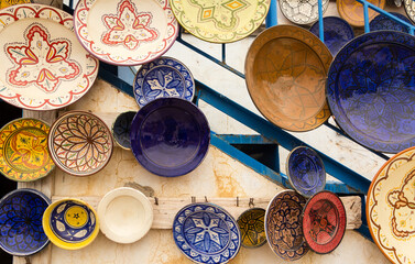 Locally made, colorful ceramic plates and bowls mounted on a wall to display to customers outside of a shop in the Atlas Mountains near Taghazout in Morocco    © Paul Jackson