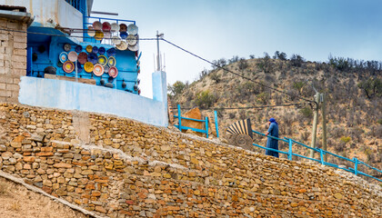 Locally made, colorful ceramic plates and bowls mounted on a wall to display to customers outside of a shop in the Atlas Mountains near Taghazout in Morocco    © Paul Jackson