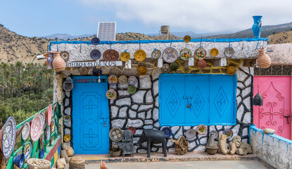 Locally made, colorful ceramic plates and bowls mounted on a wall to display to customers outside of a shop in the Atlas Mountains near Taghazout in Morocco    © Paul Jackson