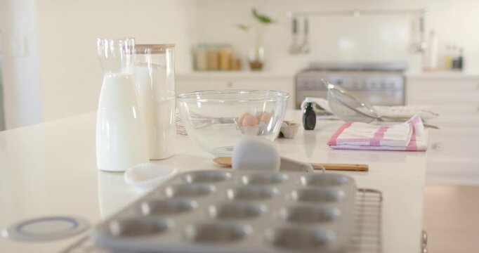 Pulling focus camera revealing muffin tin on kitchen island, showing baking prep with bowl and milk