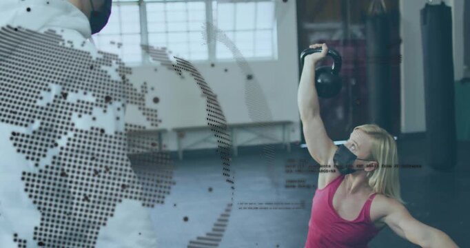 Woman pressing kettlebell up from low lunge while trainer cueing for fitness, dotted globe moving