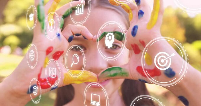 Girl holding painted hands to camera causing learning icons floating and revealing smiling face