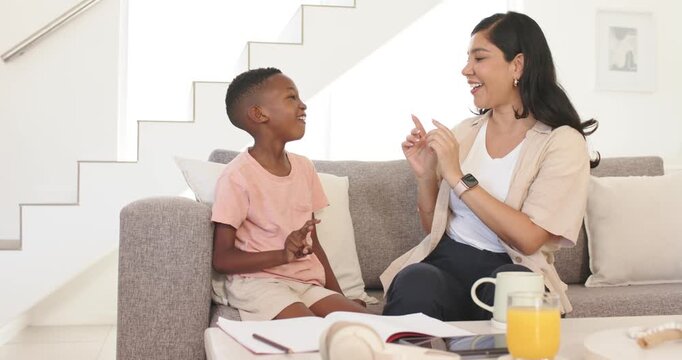 Mother and son sitting at home, child raising two fingers, mother guiding counting with tablet