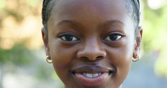 Female child smiling into laugh as camera prompts outdoors, showing slicked edges and gold hoops