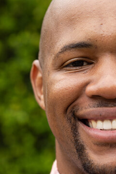 African American man smiling and facing camera in park, showing goatee, teeth and shirt collar