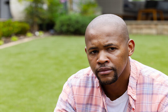 Sunlight shifting, seated man gazing past camera, contemplating backyard layout and life choices
