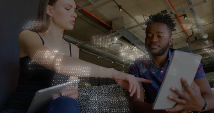 Woman pointing at man's tablet and guiding design review while man angling device on patterned sofa