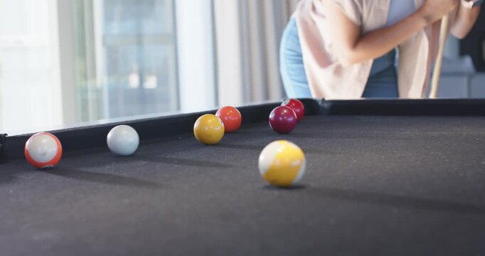 Diverse female friends playing pool in lounge, lining shots, cue contacting cue ball, sending balls