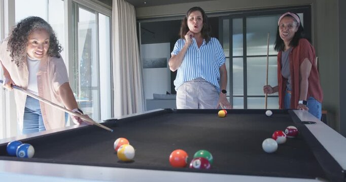 Taking shot, left player wearing jeans sending cue ball scattering on home pool table playing game