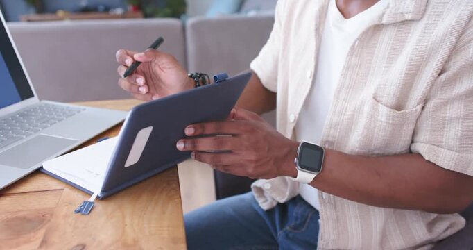 Man finishing tablet sketch and closing case reaching rack inspecting pink sweater drape for design