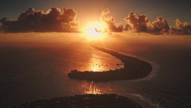 French Polynesia, Rangiroa island: Aerial view breathtaking orange sunset, vibrant colors clouds sky, winding coastline. Soft waves lap the shore, creating a serene atmosphere. Drone flight