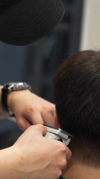 Hairdresser styling hair of a young man in a barbershop
