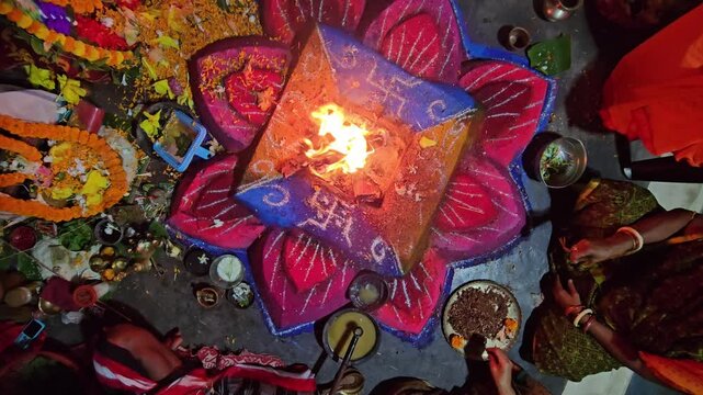 Close-up of a sacred Hindu havan (yajna) ritual with bright flames rising from a decorated fire altar. The scene captures traditional offerings, sacred powders, and ritual elements used in (puja)