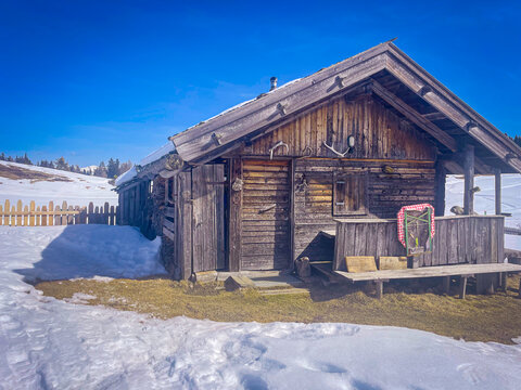 Wooden alpine malga standing on a snowy mountain pasture in Luson, Trentino Alto Adige, Bolzano, Italy