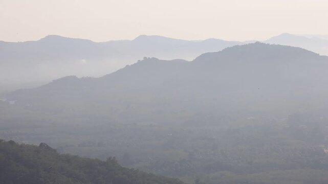 Natural video background of a high-angle atmosphere on a mountain that overlooks the surrounding scenery(mountains, trees,sea)from a scenic vantage point,with a wooden chair for sitting and resting