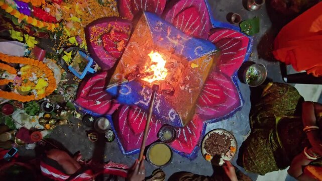 Close-up of a sacred Hindu havan (yajna) ritual with bright flames rising from a decorated fire altar. The scene captures traditional offerings, sacred powders, and ritual elements used in (puja)