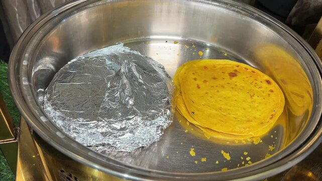 Homemade yellow-coloured Paratha kept in aluminium foil